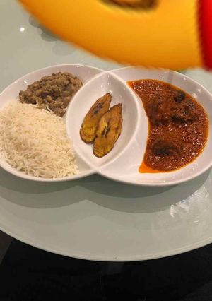 A picture of Rice and beans with plantain and stew.