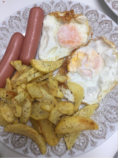 Una foto de Huevos fritos, salchichas y patatas con especias