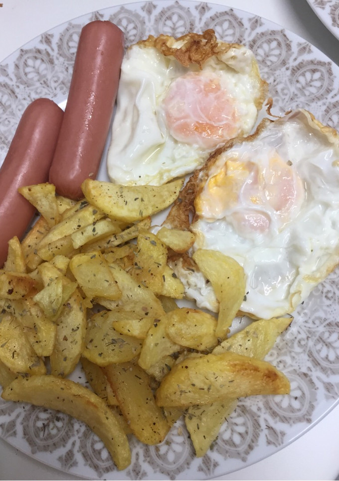 Una foto de Huevos fritos, salchichas y patatas con especias