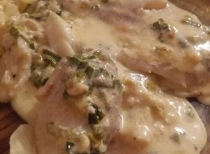 Una foto de Filet de merluza en colchón de papas con salsa crema roquefort