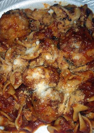 A picture of egg noodles with sauce and chicken meatballs.