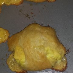 A picture of Buttery croissant filled with green onion egg and cheese mixture.