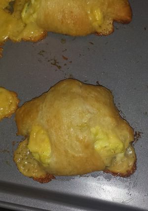 A picture of Buttery croissant filled with green onion egg and cheese mixture.
