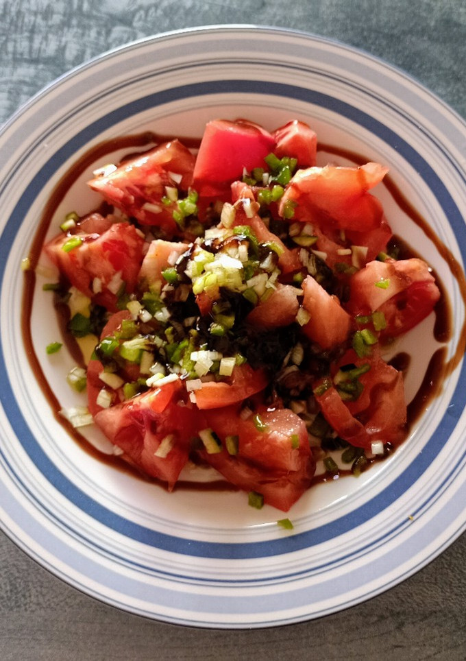 Una foto de Ensalada de tomate rosa, cebolleta, pimiento verde y calabacín