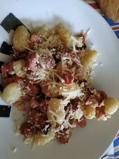 Una foto de Ñoquis con bacon, salchichas y salsa de queso