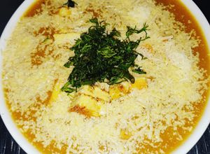 Una foto de Crema de brócoli y coliflor con cubos de huevo y queso parmesano