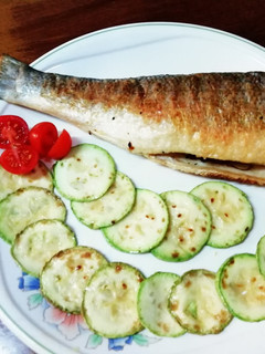 Una foto de Lubina a la plancha acompañada de calabacines y tomates cherry