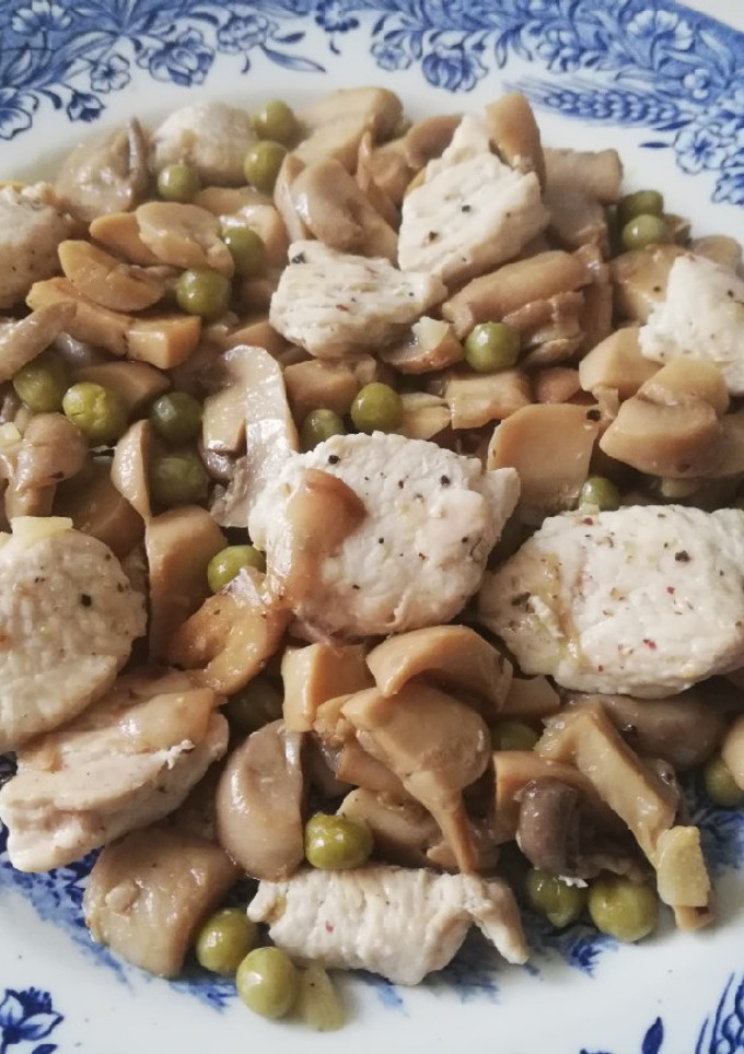 Una foto de Pechuga de pollo con champiñones al ajillo y guisantes
