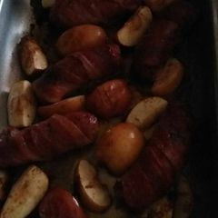 A picture of Bacon wrapped sausage with baked apples.