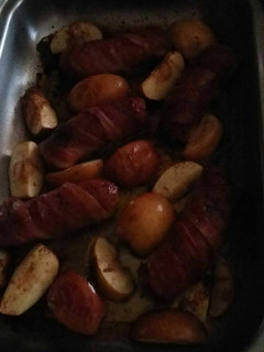 A picture of Bacon wrapped sausage with baked apples.
