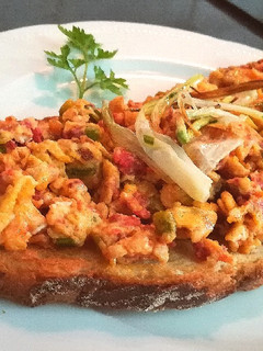 Una foto de Media tostada con huevos revueltos, ajetes y sobrasada