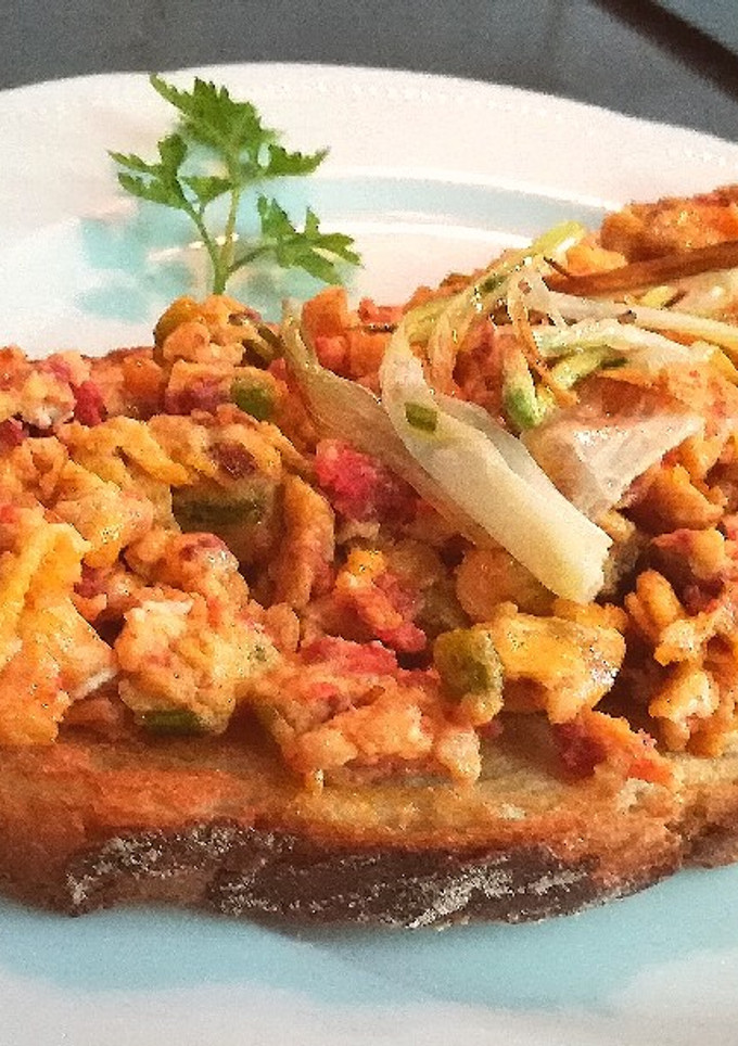 Una foto de Media tostada con huevos revueltos, ajetes y sobrasada