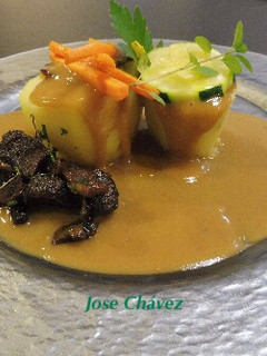 Una foto de Papas rellenas de carrillera de Cerdo en su propio jugo con setas salteadas