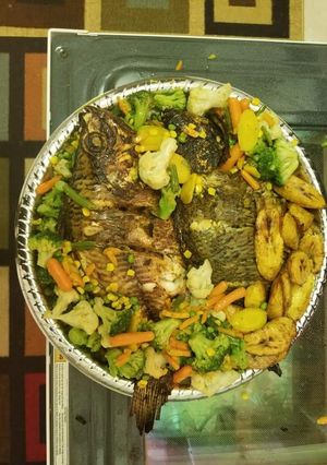 A picture of Grilled fish with fried plantain and vegetables.
