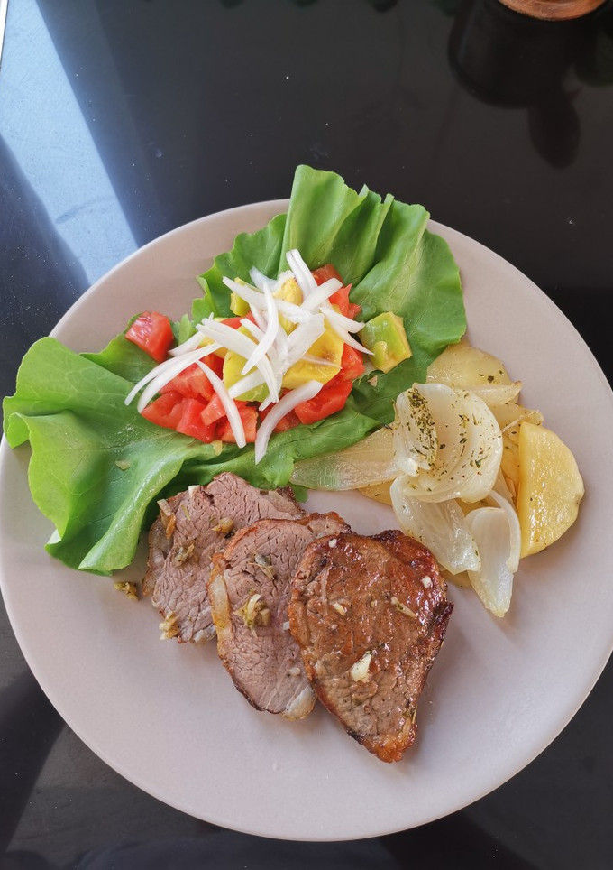 Una foto de Picaña (picanha) en cama de papas y cebollas al horno
