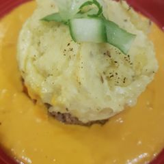 A picture of Mince and creamy mashed potatoe with an orange, squash sauce.