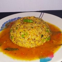 A picture of Daliya khichdi with tomato rasam.