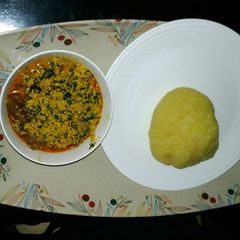 A picture of Egusi soup with yellow garri.