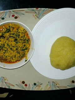 A picture of Egusi soup with yellow garri.