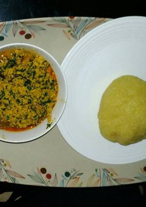 A picture of Egusi soup with yellow garri.