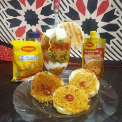 A picture of Maggi coins with bowl of veg noodles.
