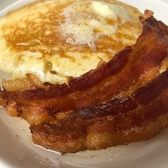 A picture of Pancakes and bacon with vanilla syrup.