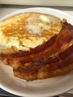 A picture of Pancakes and bacon with vanilla syrup.