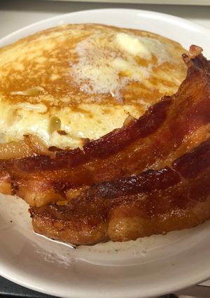 A picture of Pancakes and bacon with vanilla syrup.