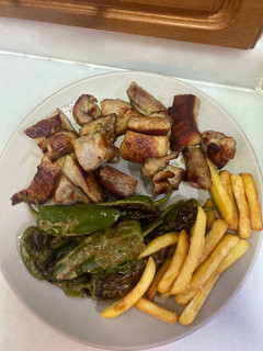 Una foto de Secreto ibérico con patatas fritas y pimientos de padrón
