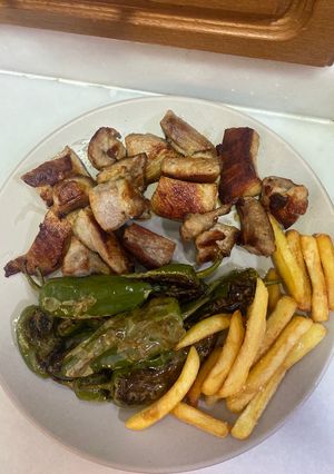 Una foto de Secreto ibérico con patatas fritas y pimientos de padrón