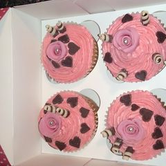 A picture of pink rose cupcakes with pink buttetcream, chocolate swirls & hearts.