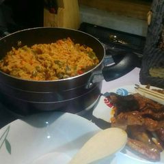 A picture of Jollof rice with veggies with peppered chicken and goat meat.