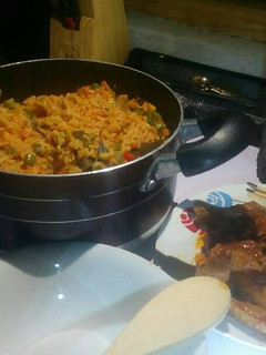 A picture of Jollof rice with veggies with peppered chicken and goat meat.