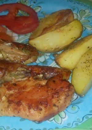 Una foto de Pollo sazonado al horno con papas y tomate