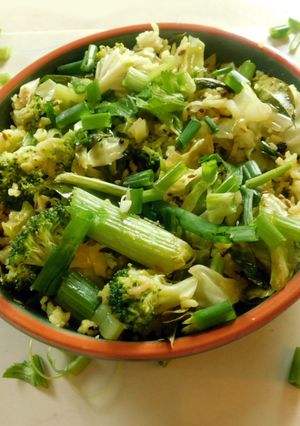 A picture of Fried rice topped with green veggies.