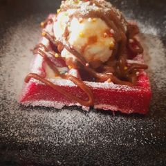 A picture of Red velvet waffle with vanilla ice cream.