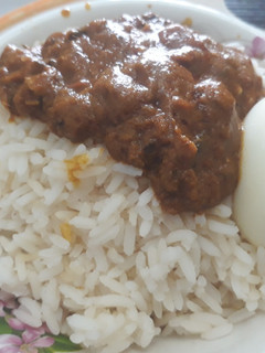 A picture of Rice with stew and boiled egg.