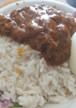 A picture of Rice with stew and boiled egg.