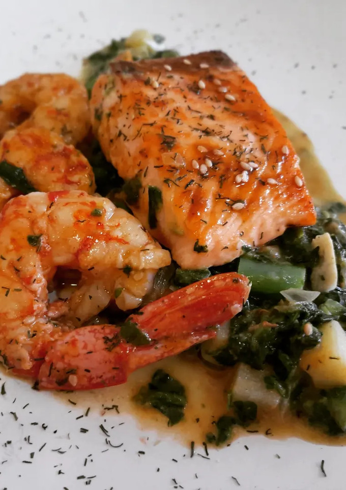 Una foto de Salmón con salsa de espinacas y verduritas con gambas