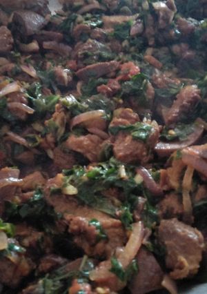 A picture of Fried pork with greens.