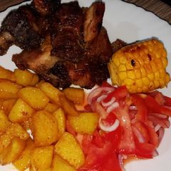 A picture of Oven baked pork with roasted potatoes and sweet corn.