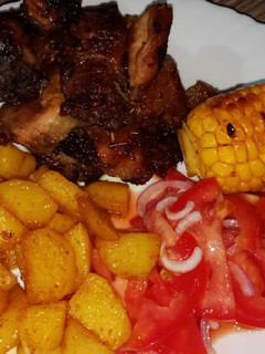 A picture of Oven baked pork with roasted potatoes and sweet corn.