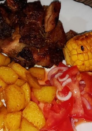 A picture of Oven baked pork with roasted potatoes and sweet corn.