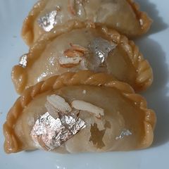 A picture of Mava gujiya dipped in sugar syrup.
