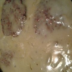 A picture of grilled hamburgers smothered in gravy.