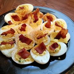 A picture of deviled eggs with bacon.