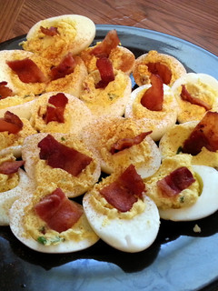 A picture of deviled eggs with bacon.