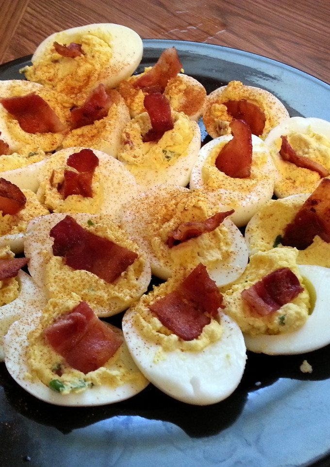 A picture of deviled eggs with bacon.