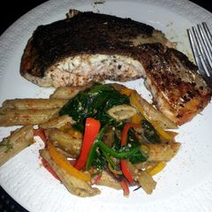 A picture of jerk salmon and penne pasta with bell peppers eggplant &spinach.