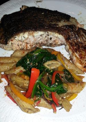 A picture of jerk salmon and penne pasta with bell peppers eggplant &spinach.